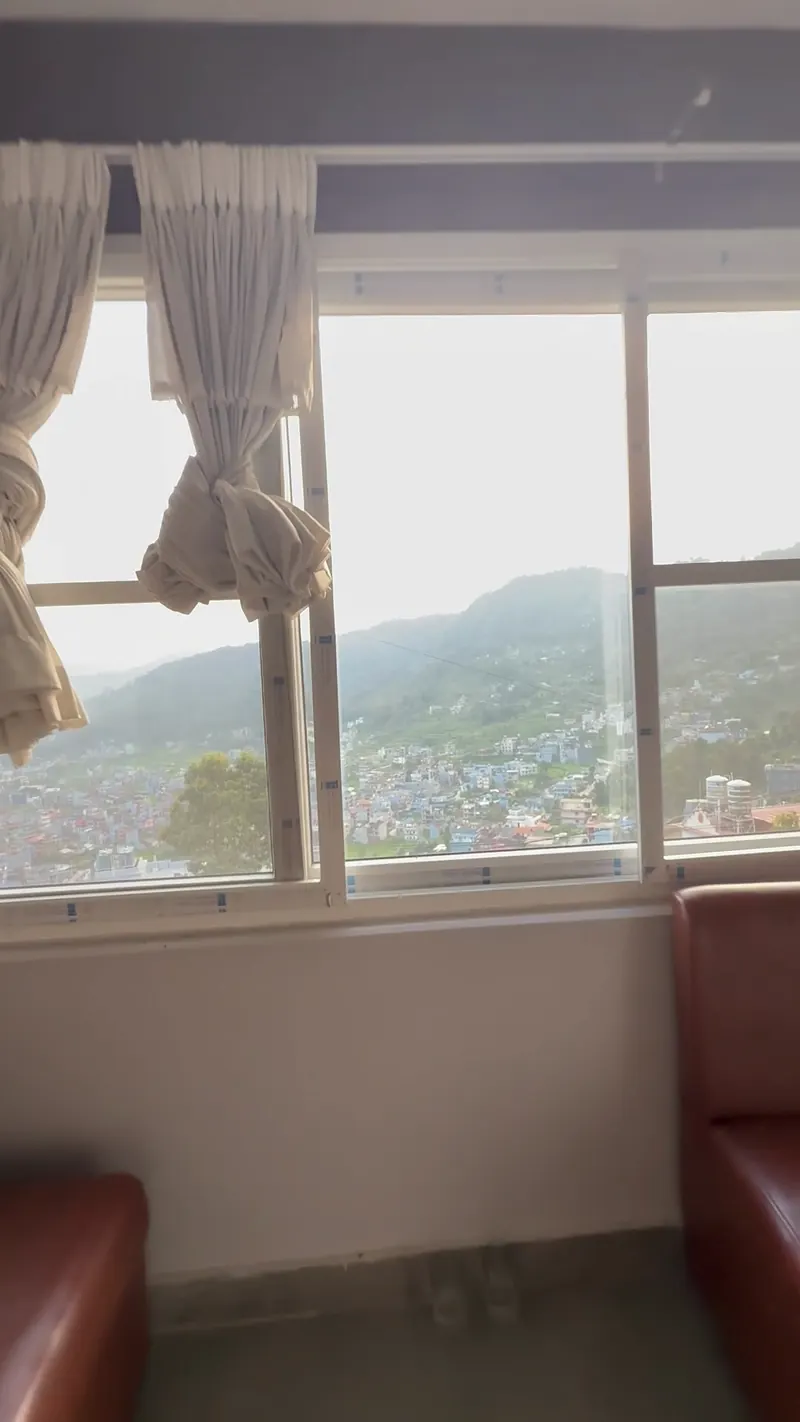 A cabin with leather sofas and a window looking out over Pokhara valley